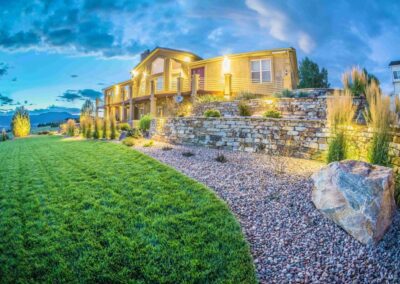 Illuminated night scene of a home with a remodled landscape design including a new retaining wall and outdoor lighting