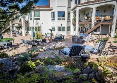 Patio and deck furniture outside of large house that has recently received a fresh landscape design