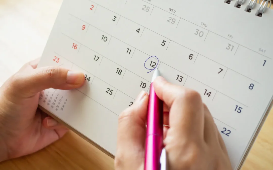 Hand marking on a calendar the best time to hire a landscape designer